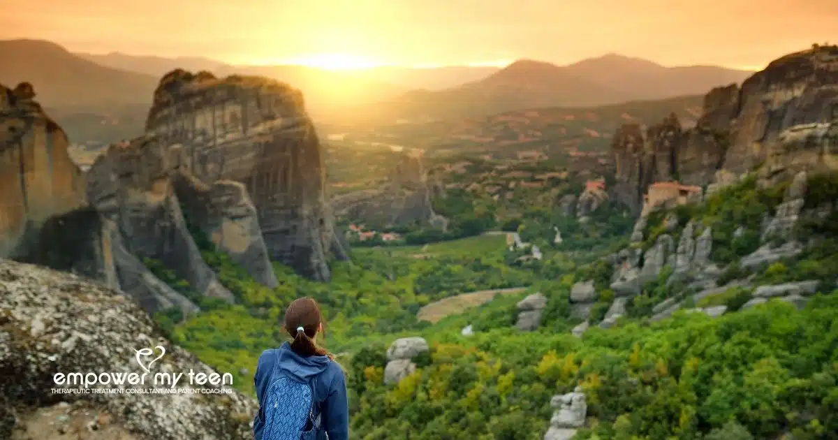 Exploring Teen Therapeutic Options for Struggling Teens: Teen looking over a serene mountain landscape at sunset.
